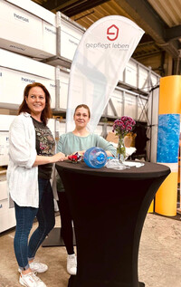 Zwei MItarbeiterinnen von gepflegt leben erwarten am Messestand interesierte Besucher:innen